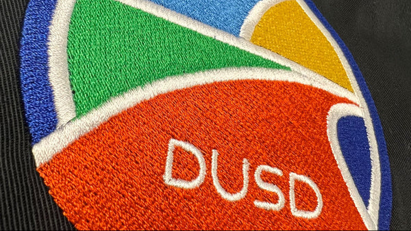 Colorful patch with 'DUSD' text on a black background